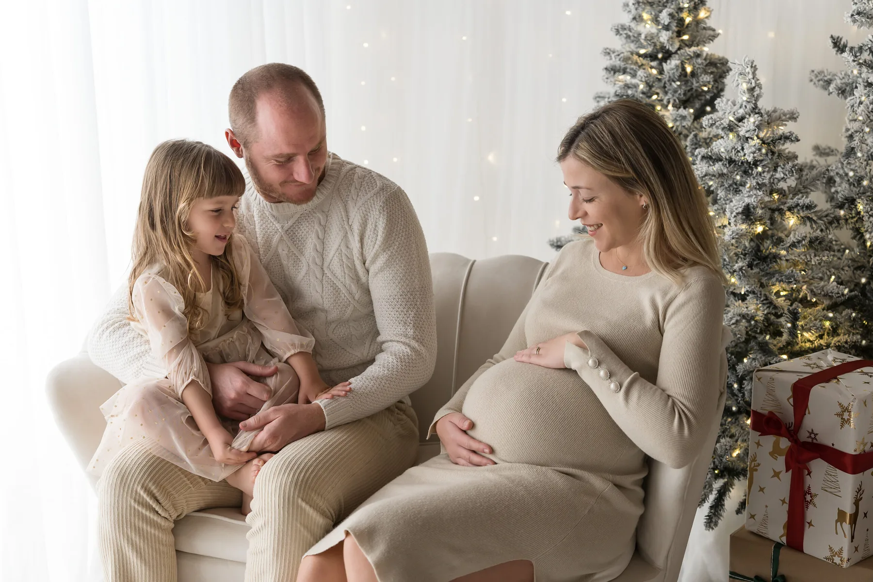 Mamma in attesa con la figlia davanti all&rsquo;albero di Natale