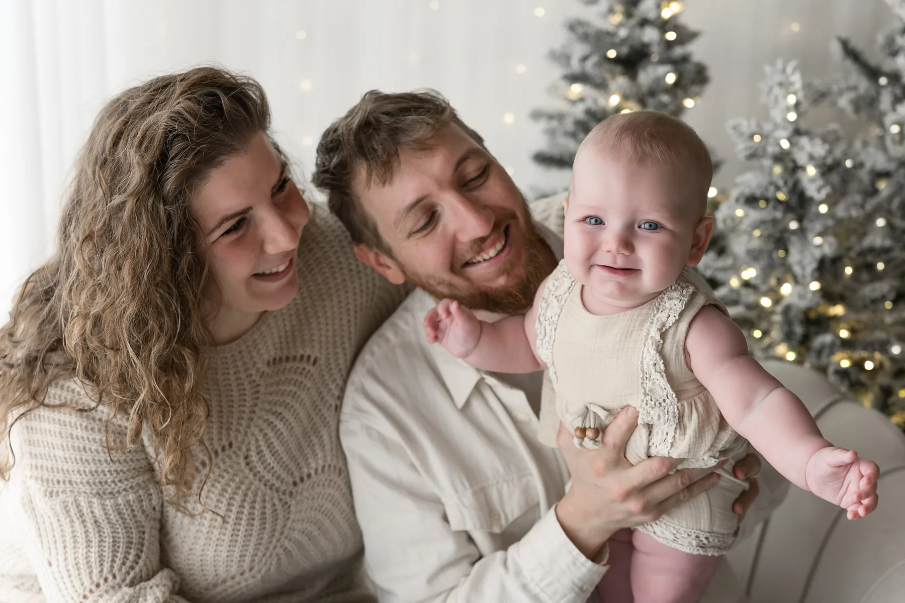 Coppia con la bambina sorridente in braccio nel set di Natale